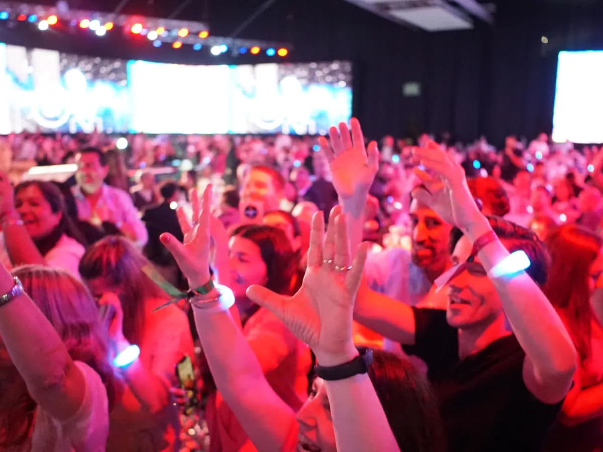 Invitados con las manos en alto y pulseras LED encendidas en la gala Dominicana te sonríe, en La Rural
