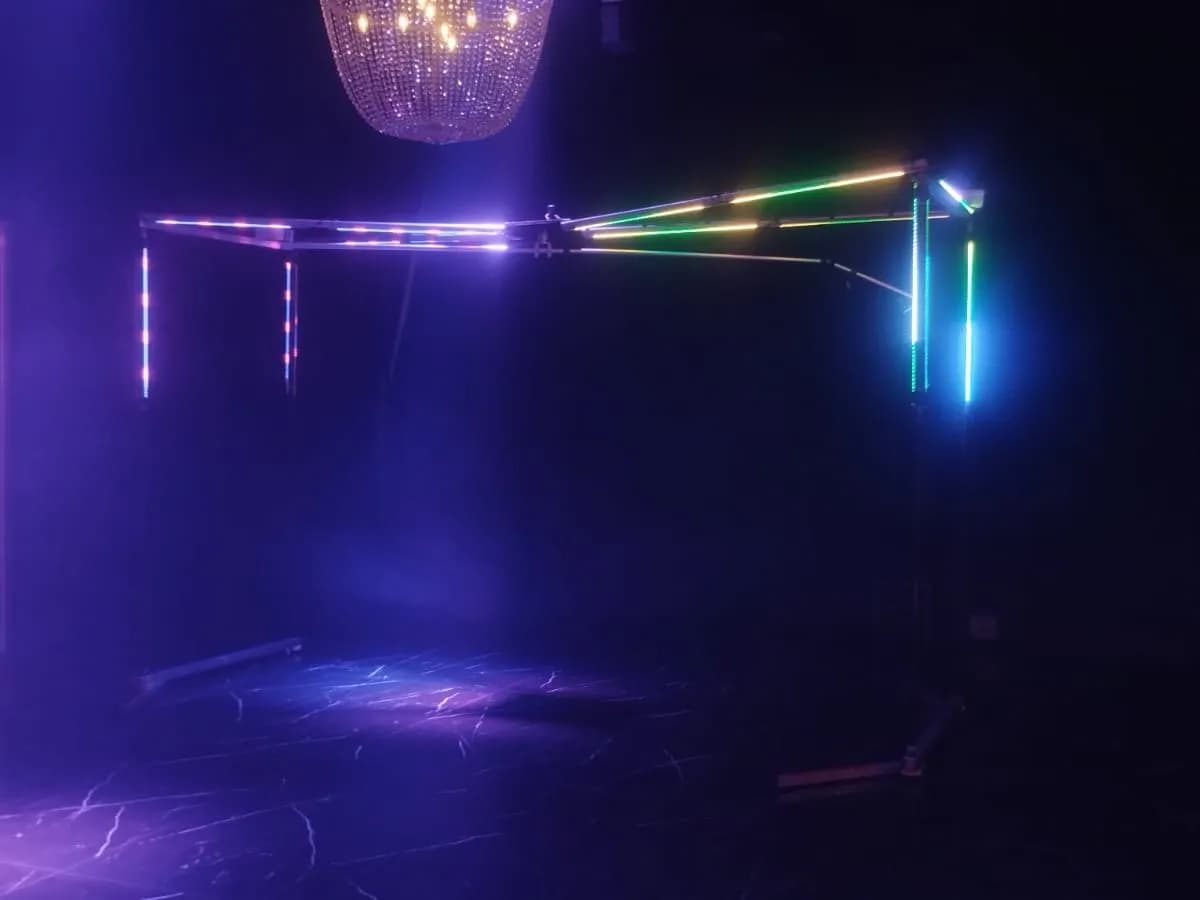 Estructura con luces LED de colores en un salón a oscuras, preparada para una activación en un evento
